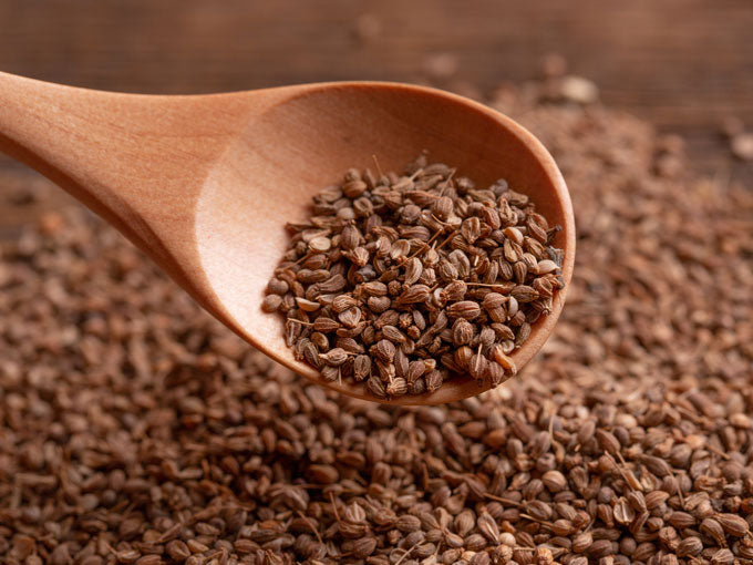 Wooden spoon filled with brown anise seeds on a textured brown background