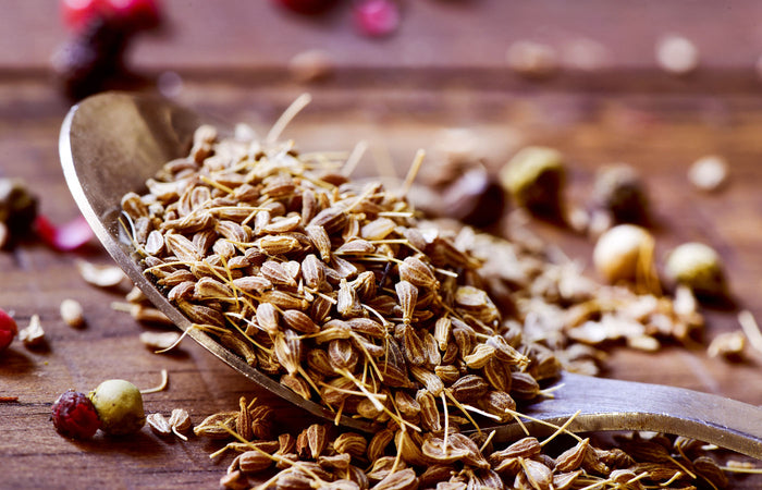 Wooden spoon filled with dried anise seed on a wooden surface