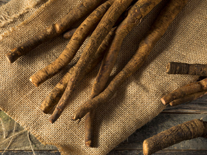 burdock root on a rustic wooden surface with burlap cloth