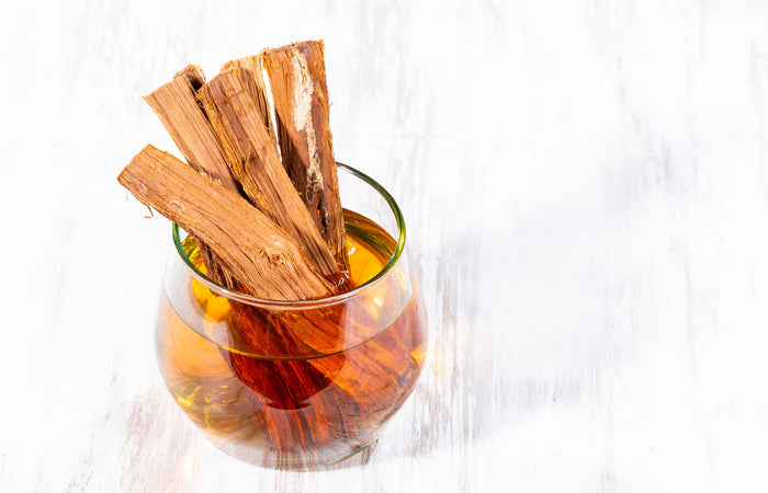 Glass of iced tea with Cat's claw bark on a white background