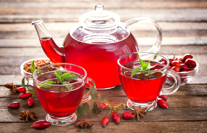 Teapot and cups of rose hips tea with rosehips on a wooden surface