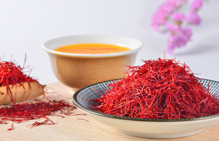 Dried saffron on a plate with a cup of tea in the background