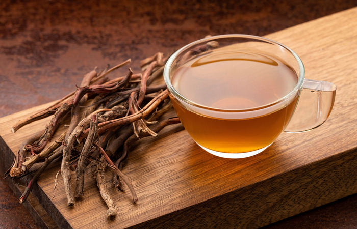 Glass cup of tea with sarsaparilla root  tea leaves on a wooden surface