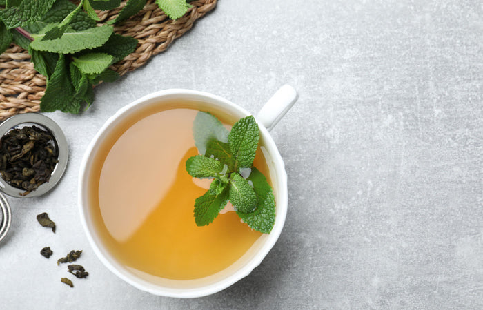 Tea cup with spearmint leaves on a gray surface