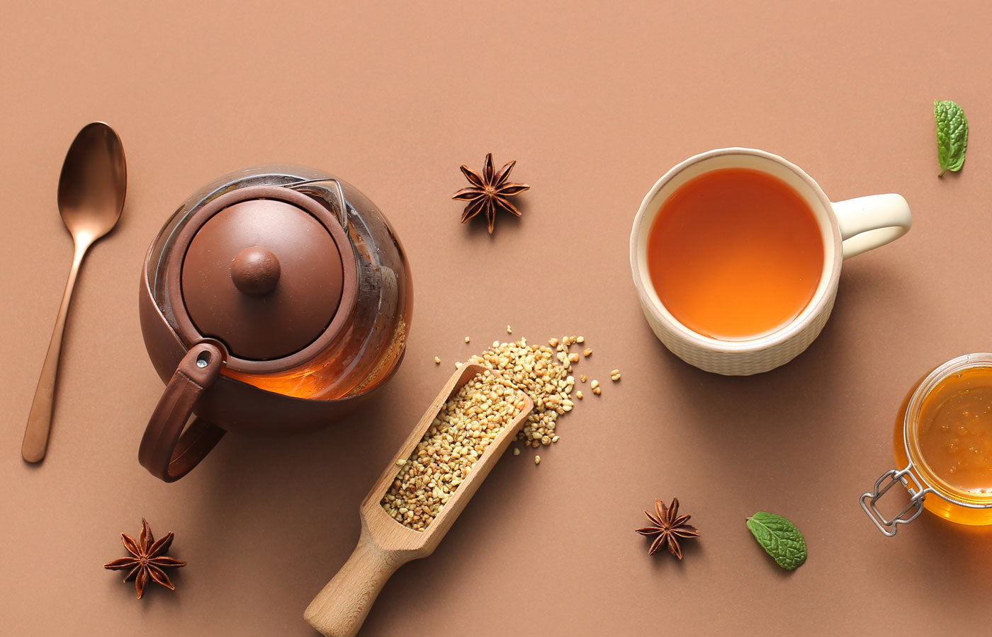 Tea-making setup with teapot, cup of Anise seed tea, spoon, and tea leaves on a brown background
