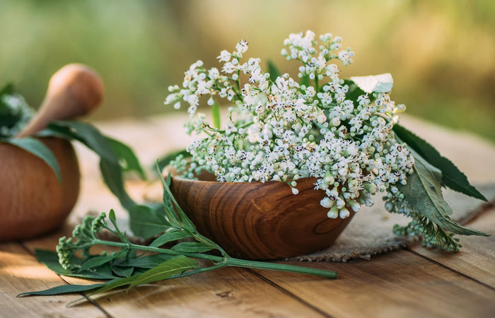 Wooden bowl with white valerian flowers on a wooden surface