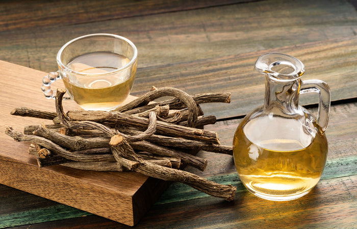 Glass of tea, valerian roots, and a carafe on a wooden surface