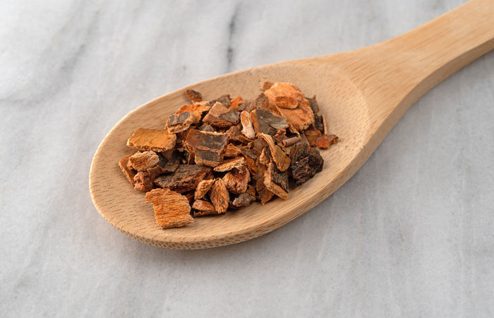 Wooden spoon with dried wild cherry bark  on a marble surface
